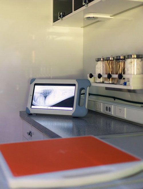 A tablet displaying an image on a kitchen counter with spice racks in the background.